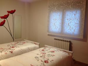 阿尔格达斯Apartamento Turistico Cigüeña de Arguedas的一间卧室设有两张床和一扇红色花卉窗户。