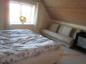 SpottrupBakkegården Homestay的一间卧室配有一张床、一张沙发和一个窗口