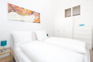 柏林Apartment Uthman Berlin-Neukölln的卧室配有2张白色的床和墙上的绘画作品