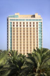 卡尔巴拉Karbala Rayhaan Hotel & Suites的一座高大的建筑,前面有棕榈树
