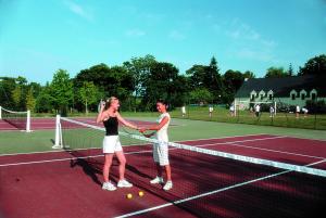 贝隆河畔日克VTF Ker Belen的两个女人在网球场上摇手翻过网