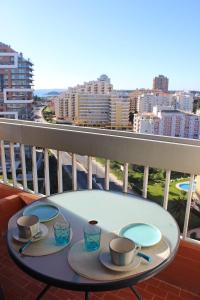 波尔蒂芒Praia da Rocha Tarik的阳台上的桌子上放有盘子和杯子