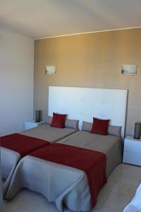 波尔蒂芒Praia da Rocha Tarik的一间卧室配有两张带红色枕头的床