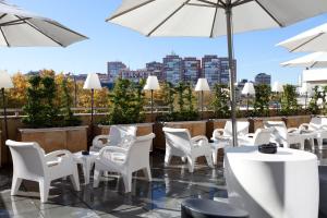 马德里马德里别墅酒店的庭院配有白色的桌椅和遮阳伞。