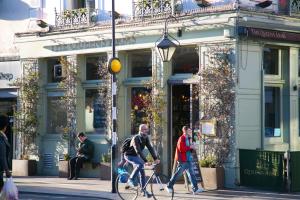 伦敦维多利亚便捷酒店的两个男人骑着自行车沿着商店前面的街道行驶