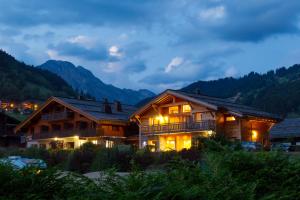 大博尔南Chalet-Hotel et Spa Le Delta的夜晚的木屋,以群山为背景