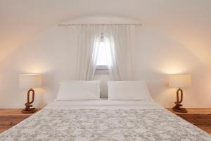 佩里沃罗Orabel Suites Santorini (Adults Only)的卧室配有带两盏灯的白色床