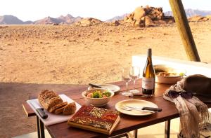 塞斯瑞姆沙漠箭袋营旅馆的一张桌子,上面放着食物和一瓶葡萄酒及酒杯