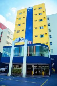 容迪亚伊Millian Hotel的一座黄色和蓝色的建筑,外面有一辆汽车