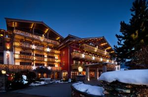 基茨比厄尔Kitzhof Mountain Design Resort 4 Sterne Superior的一座大建筑,上面有灯光,在雪中