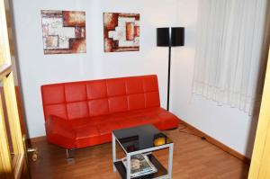 圣地亚哥－德孔波斯特拉Pensión Residencia Fornos的客厅里一张红色的沙发,配有桌子