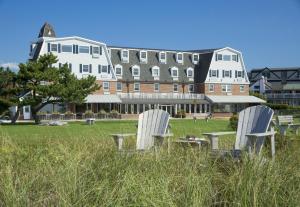 米德尔敦纽波特海滩套房酒店的两把白色椅子坐在建筑物前面的草上