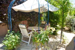 Pierrevert维拉维瓦维塔勒住宿加早餐旅馆的花园的遮阳伞下的桌椅