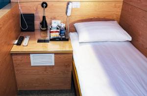 内排VATC2号航站楼胶囊旅馆的一间卧室配有一张床和一张带电话的书桌