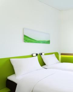 万隆万隆亚非宜必思快捷酒店的绿墙客房内的两张白色床