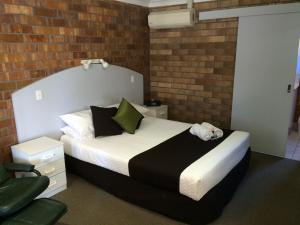 Miles迈尔斯奥拜汽车旅馆的一间卧室设有一张床和砖墙