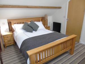 Capel HendreKings Head的一间卧室配有一张带枕头的大型木制床。