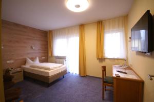 巴特欧波维德纳酒店的一间卧室配有一张床、一张书桌和一台电视。