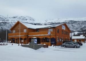 索克约森Henriksen Gjestestue的一座大型的木制建筑,有一辆汽车停在雪地里