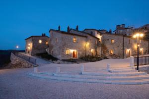 Castel del GiudiceBorgotufi Albergo Diffuso的一座大型石头建筑,前面有灯