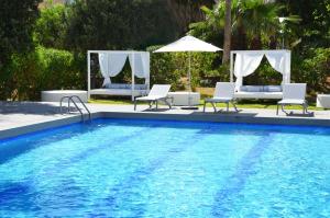 普拉亚登博萨Apartamentos Vibra Tivoli的一个带椅子和遮阳伞的游泳池