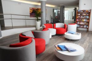 普拉亚登博萨Apartamentos Vibra Tivoli的图书馆配有红色和白色的椅子和桌子