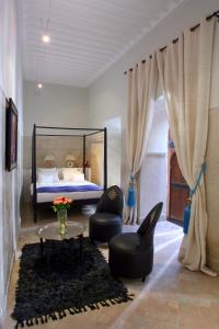 马拉喀什里亚德达阿森旅馆的一间卧室配有一张床、两把椅子和一张桌子