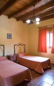 马拉加马拉加蒙特斯乡村民宿 - 佩德格尔斯农场的一间卧室设有两张带红色床单的床和窗户。