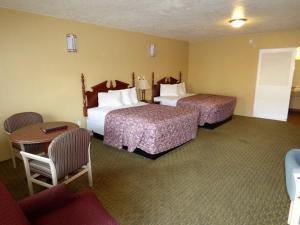 圣乔治经济套房酒店的酒店客房带两张床和一张桌子以及椅子。