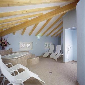 阿科奥利沃酒店的带椅子和浴缸的客房,拥有木制天花板