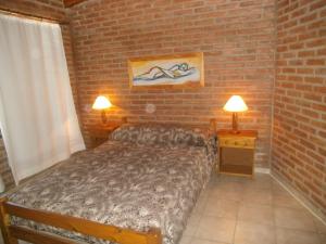 维拉卡洛斯帕兹Cabañas Tio Willy的一间卧室配有一张床、两盏灯和砖墙