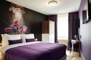阿姆斯特丹阿姆斯特丹缪斯精品酒店的一间卧室配有一张紫色床,墙上挂有花卉画