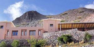 伊鲁亚Hotel Iruya的岩石山前的粉红色建筑