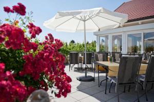 索梅劳森菲尔小夫－温古特旅馆的庭院设有桌子和白色的遮阳伞,鲜花盛开。