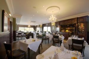 格洛斯特哈顿苑酒店 的餐厅配有白色的桌椅和吊灯