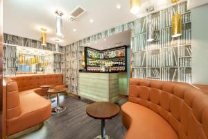 伦敦伦敦帕丁顿美居酒店的一间设有橙色座椅的餐厅和一间酒吧