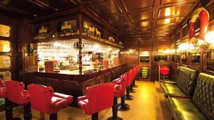 库克斯港司图茨公寓式酒店 - 斯坦普乐酒店的餐厅内带红色椅子的酒吧