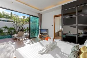 奈扬海滩普吉岛泳池别墅的一间卧室配有一张大床和电视