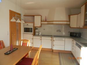 文斯Ferienwohnung Gasser的厨房配有白色橱柜和一张带椅子的木桌
