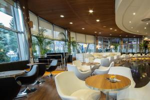 新戈里察Perla, Resort & Entertainment的餐厅设有白色的椅子和桌子以及窗户。