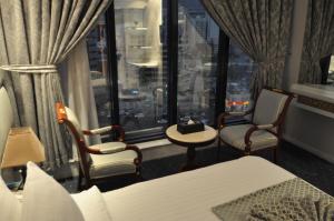 麦加Montana Al Azizia Hotel的客房设有床、两把椅子和窗户。