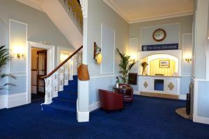赖德皇家滨海酒店的走廊上铺有蓝色地毯,墙上设有楼梯和时钟