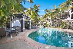 黄金海岸蓝水公寓酒店的度假村的游泳池,配有桌椅和棕榈树