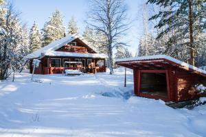 SuonenvaaraLoma Rinteelä的雪地里的小木屋,有雪覆盖的树木