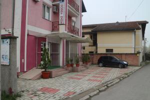 贝尔格莱德Kuca Veljovica的停在粉红色建筑前面的汽车
