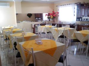 CastanhalEstação Hotel的配有桌椅的房间,配有黄色和白色的桌布