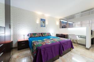 大加那利岛拉斯帕尔马斯Suites Garden Loft Dalí的一间卧室配有一张带紫色毯子的床