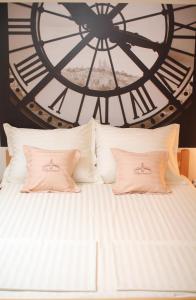 诺维萨德丰泽公寓式酒店的时钟前的白色床和两个枕头