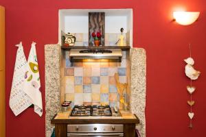阿罗纳Casa Corte Alla Rocca的厨房配有炉灶和红色墙壁