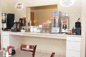 Corydon科里登速8酒店的咖啡店的柜台,配有桌子和椅子